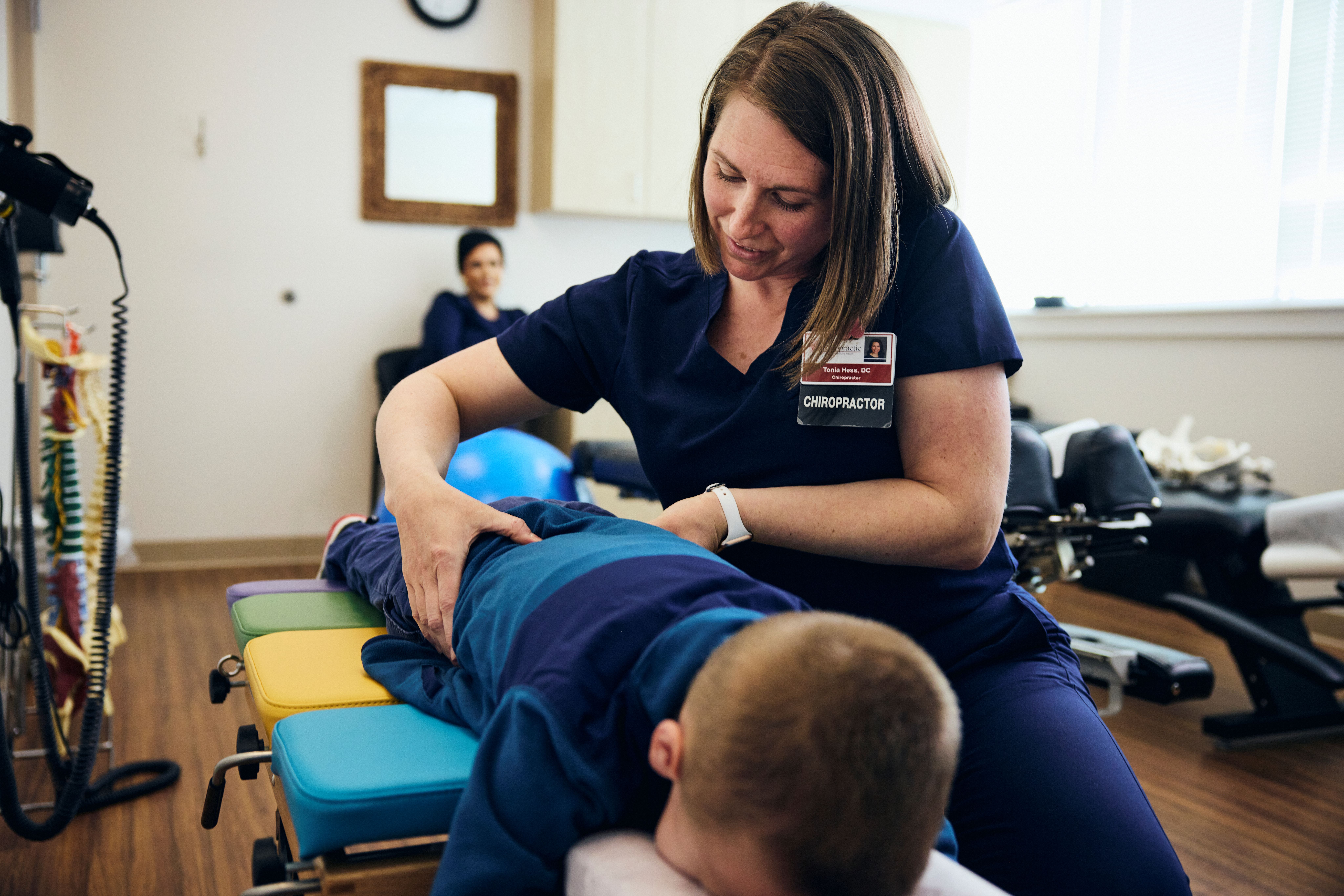 A chiropractor makes an adjustment while a child lies on the chiropractic table.